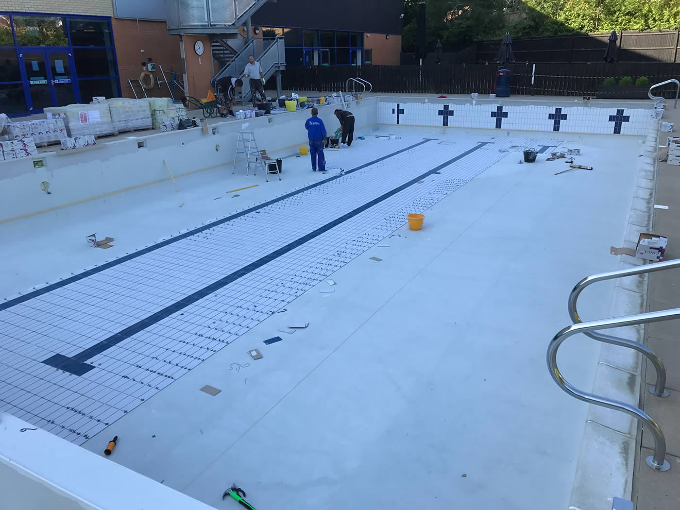 Men tiling an outside swimming pool